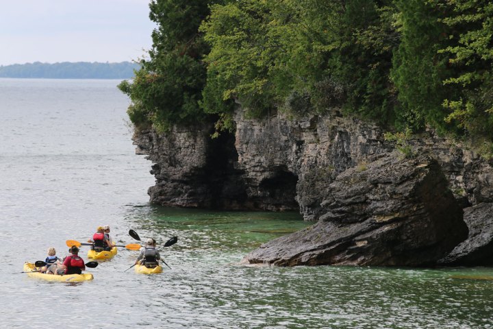 a scenic photo of Cave Point County Park with kayakers in the distance