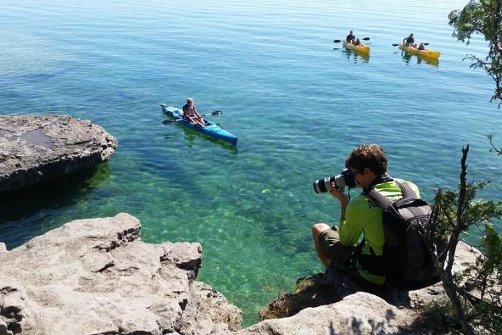 a group of people on a rock next to a body of water